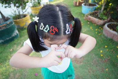 High angle view of girl making heart shape while standing outdoors