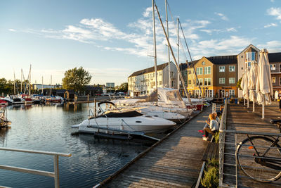 Boats moored at harbor in city during sunset