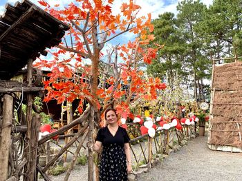 Portrait of young woman standing by tree