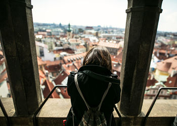 Rear view of woman looking at cityscape from balcony