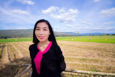 Portrait of smiling young woman standing on field
