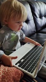 Rear view of boy using mobile phone at home