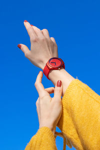 Cropped hand of person holding key against blue background