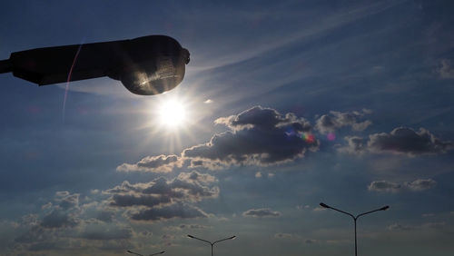 Low angle view of sunlight streaming through clouds during sunset