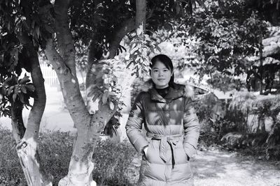 Portrait of happy young woman standing in park