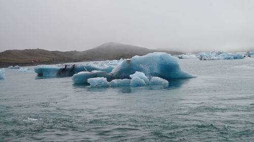 View of icebergs in sea against clear sky