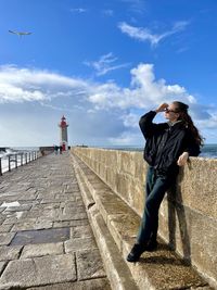 Rear view of man standing on pier against sky