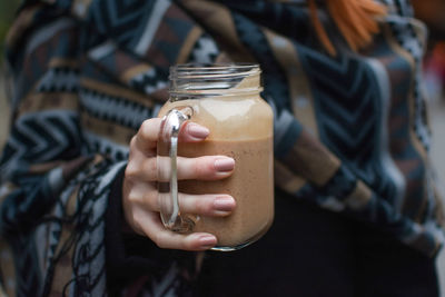 Midsection of woman holding smoothie in mason jar