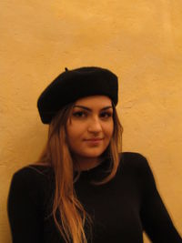 Portrait of smiling young woman standing against wall