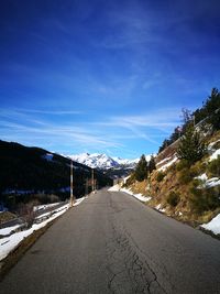 Road by snow covered mountain against sky