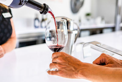 Close-up of hand pouring wine in glass