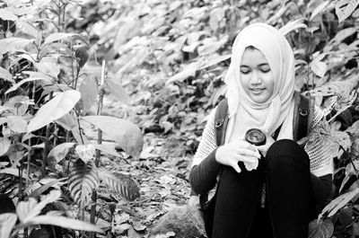 Smiling young woman wearing hijab while sitting by plants