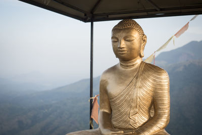 Man standing by cross against mountain range against sky