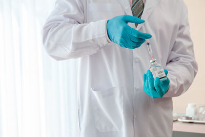 Midsection of scientist holding syringe with vial in laboratory