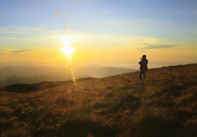 Man standing on field against sky during sunset