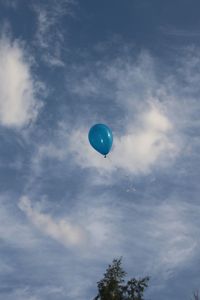 Low angle view of balloon flying against cloudy sky
