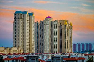 Modern buildings in city against sky during sunset