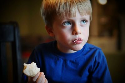 Thoughtful boy eating bread at home