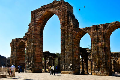 Rear view of man standing against historic building against clear sky