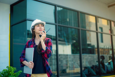 Young woman looking away while standing against buildings