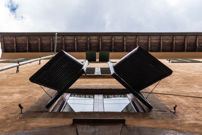 Empty chairs and table by building against sky