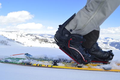 Low section of man with snow on mountain against sky