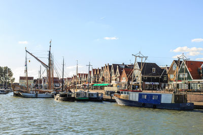 Sailboats moored at harbor against sky in city