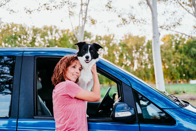 Woman holding dog by car