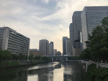 Modern cityscape by river against sky
