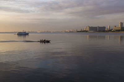 Boats in sea at sunset