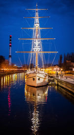 Reflection of illuminated boats moored in water at night