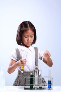 Schoolgirl performing scientific experiment against blue background