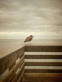 Pier on sea against cloudy sky