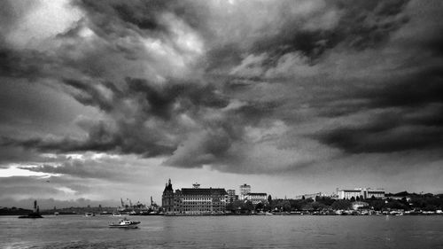 City at waterfront against cloudy sky