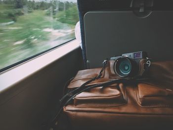 Close-up of camera and leather bag in train