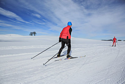 People skiing on snowy field against sky