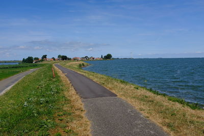 Road by sea against blue sky