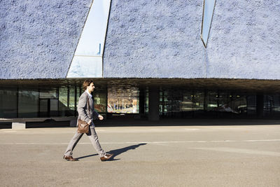 Side view of businessman walking on road in city