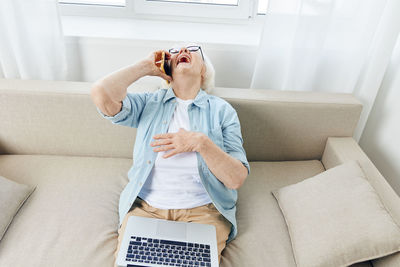 Midsection of woman using laptop while sitting on sofa at home