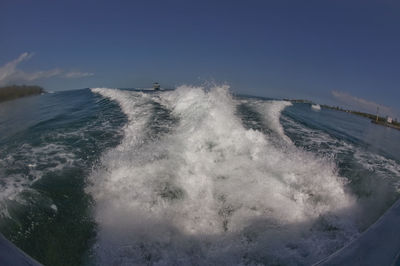 Waves splashing on shore against sky