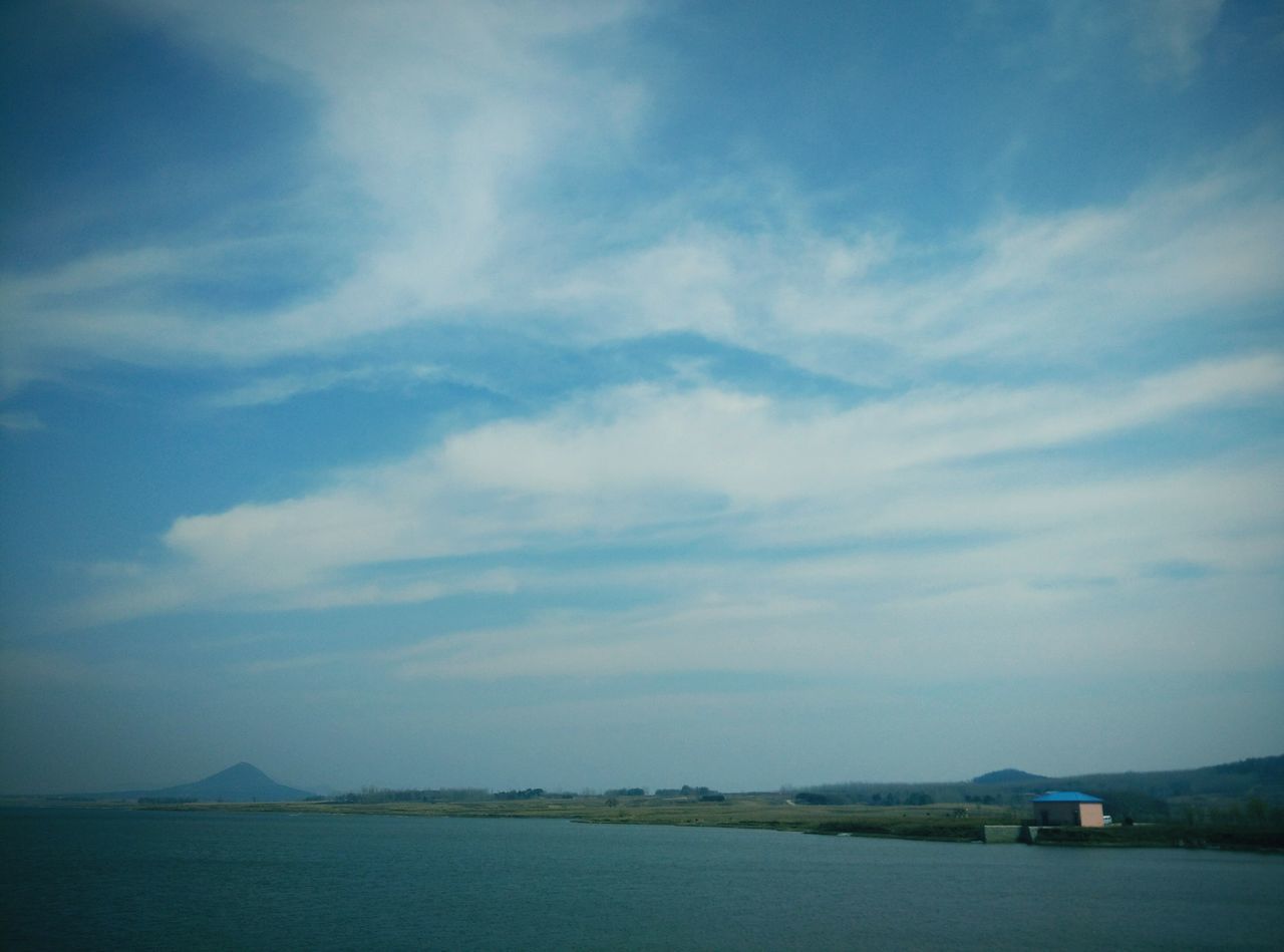 water, sky, tranquil scene, tranquility, scenics, sea, beauty in nature, cloud - sky, waterfront, nature, cloud, mountain, blue, idyllic, cloudy, landscape, outdoors, day, beach, non-urban scene