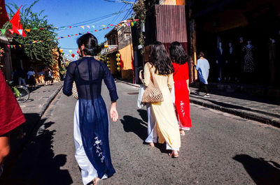 Rear view of people walking on street in city