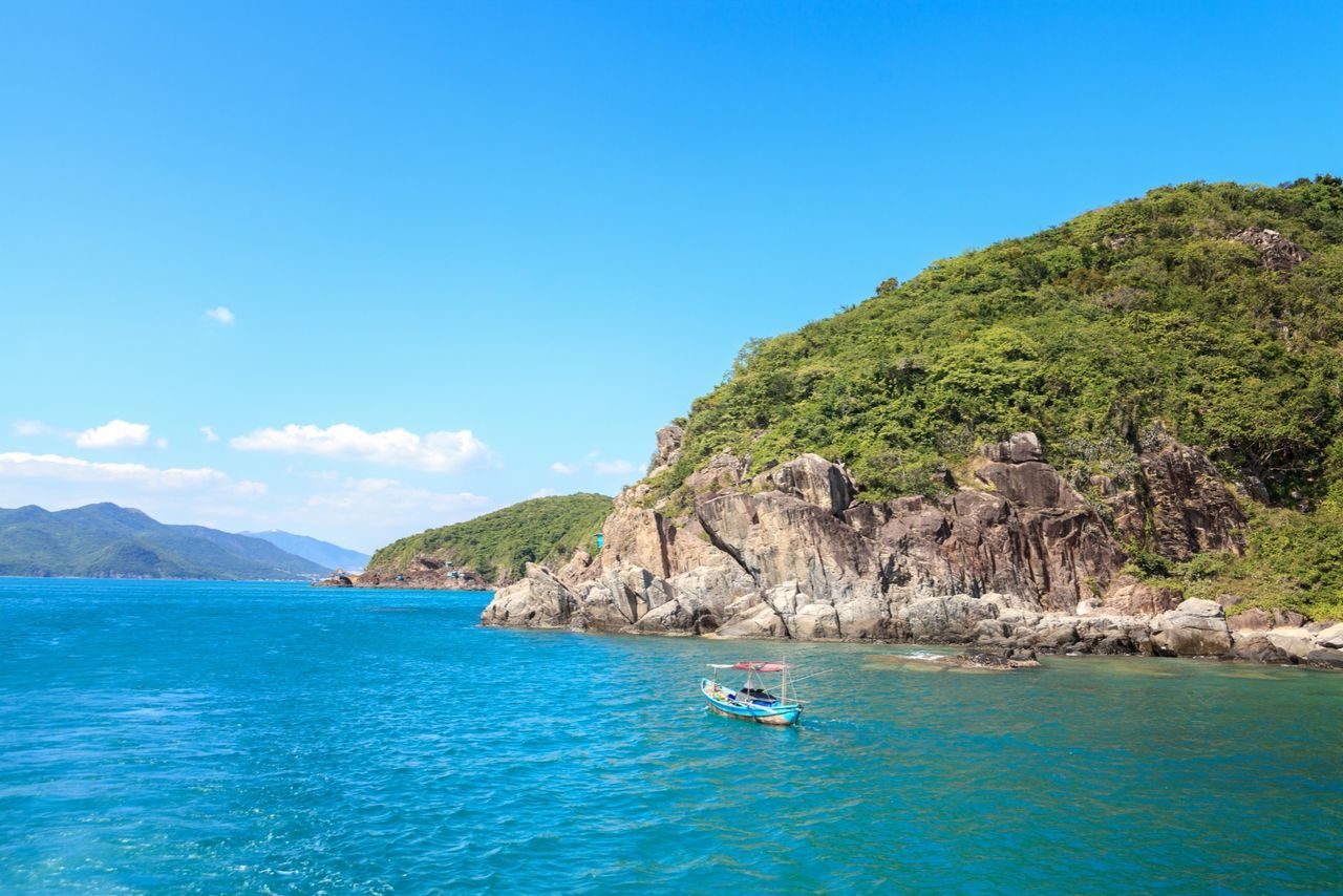 sea, water, mountain, blue, nautical vessel, scenics, tranquil scene, tranquility, beauty in nature, transportation, cliff, rock formation, boat, nature, waterfront, mode of transport, sky, clear sky, idyllic, vacations