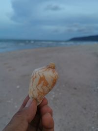 Hand holding ice cream cone on beach