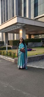 Full length portrait of woman against building in city