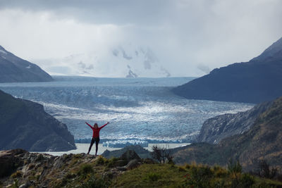 Rear view of person standing on shore against sky