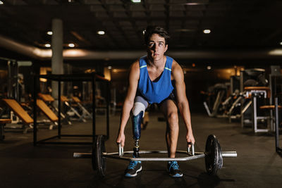 Full length of man with prosthetic legs exercising in gym