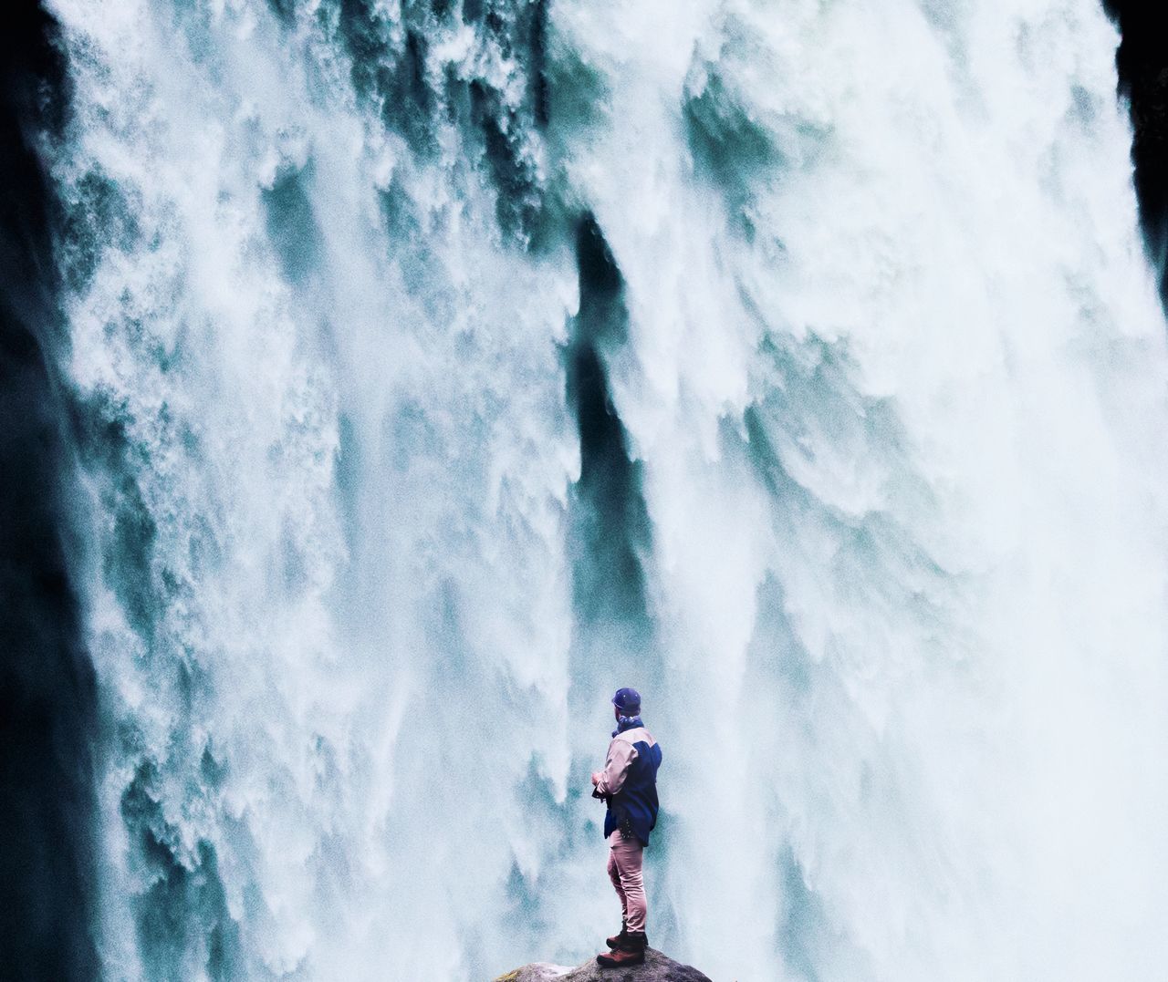 LOW ANGLE VIEW OF MAN STANDING AT WATERFALL