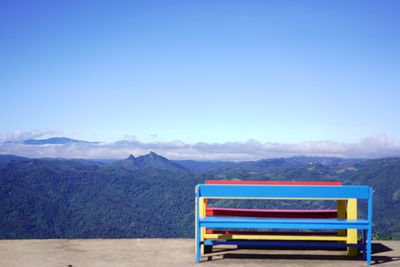 Deck chairs on bench against blue sky