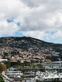 Aerial view of townscape by harbor against sky